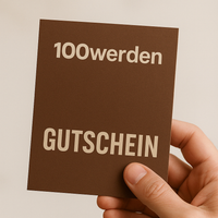 Eine Hand hält den 100werden Gutschein von Luke Jaque-Rodney - eine braune Karte mit weißer Aufschrift, perfekt als digitales Produkt für den Versand per E-Mail.